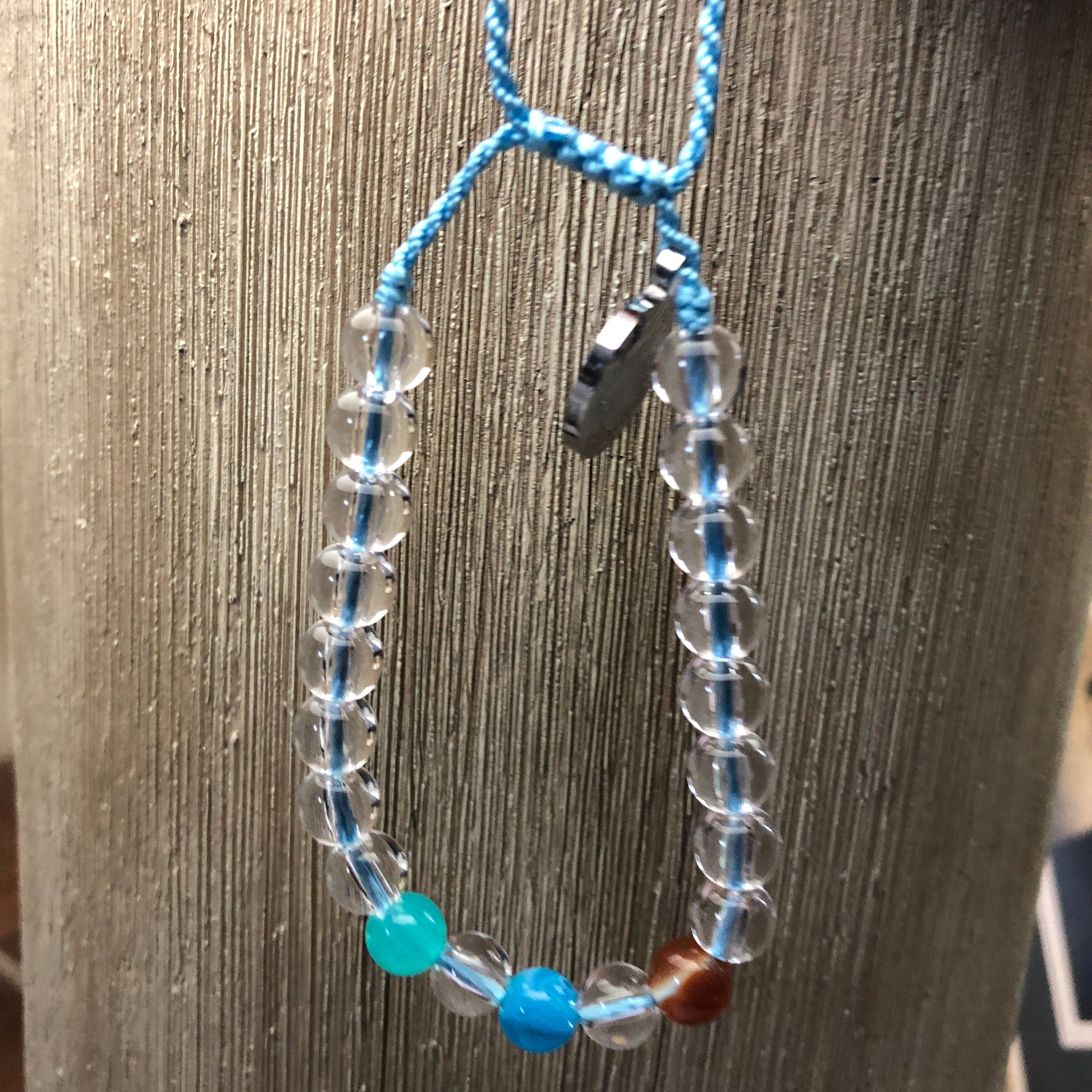 Bracelet with clear beads and blue accents on a textured surface