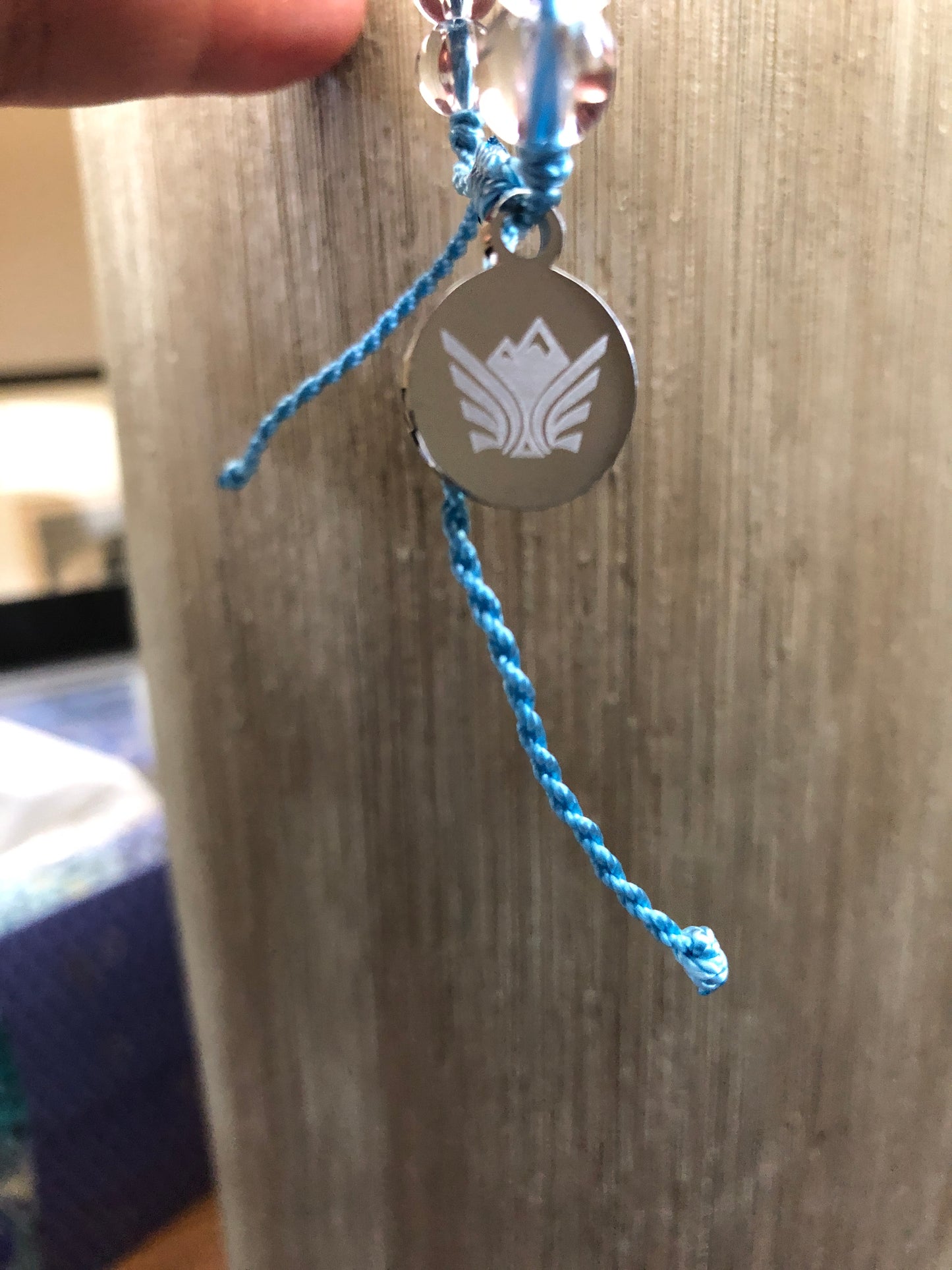 Bracelet with blue cord and metal charm on a wooden surface