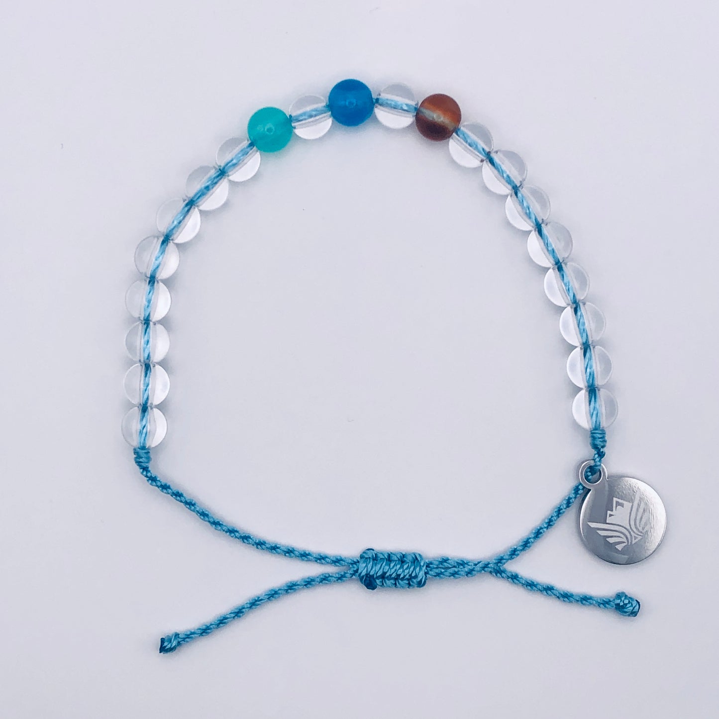 Blue beaded bracelet with a silver charm on a light gray background