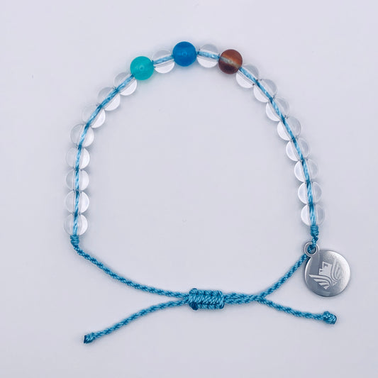 Blue beaded bracelet with a silver charm on a light gray background